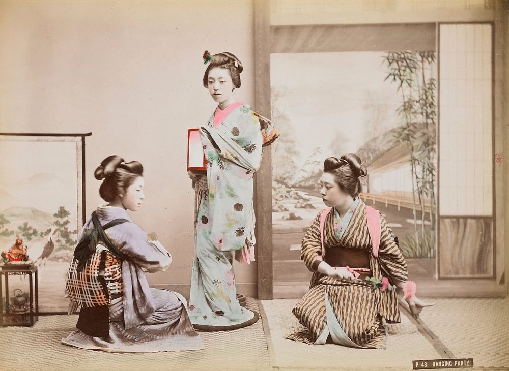 Three young women wearing traditional Japanese costumes; standing woman at center wears light blue kimono with grey and pink…