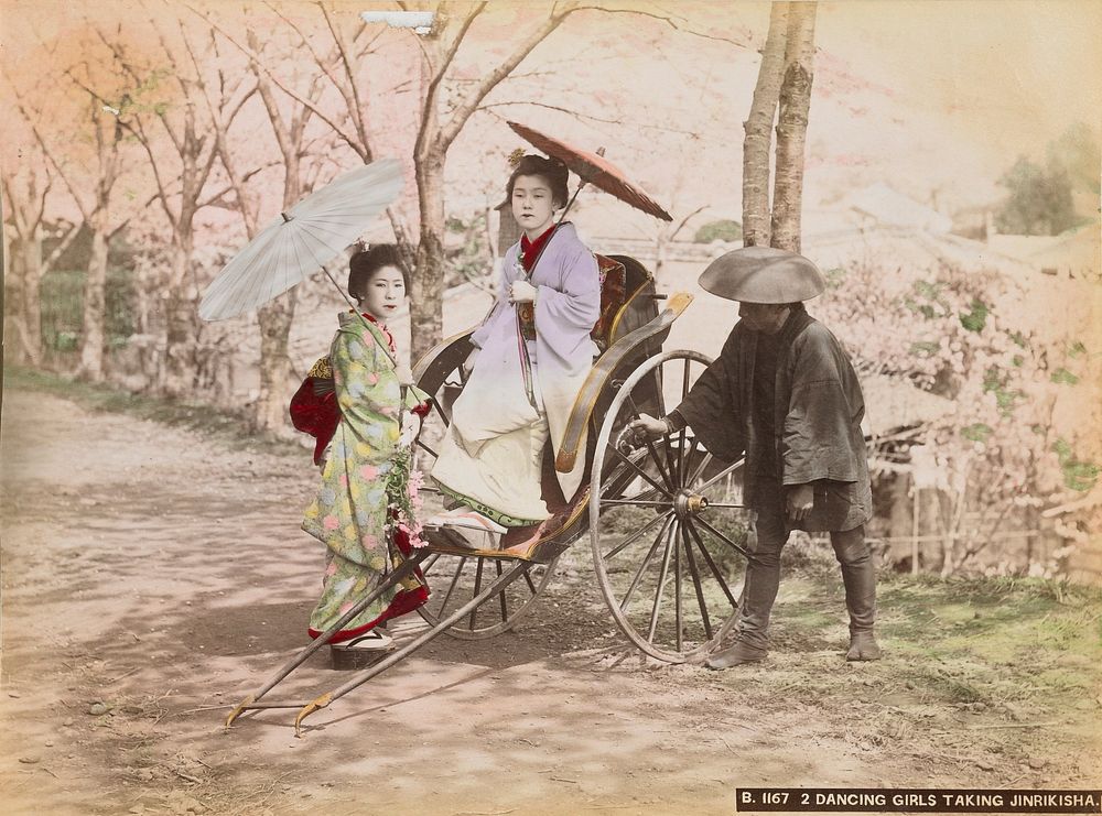 two young women wearing traditional Japanese costumes and carrying parasols; standing woman at left wears pale green kimono…