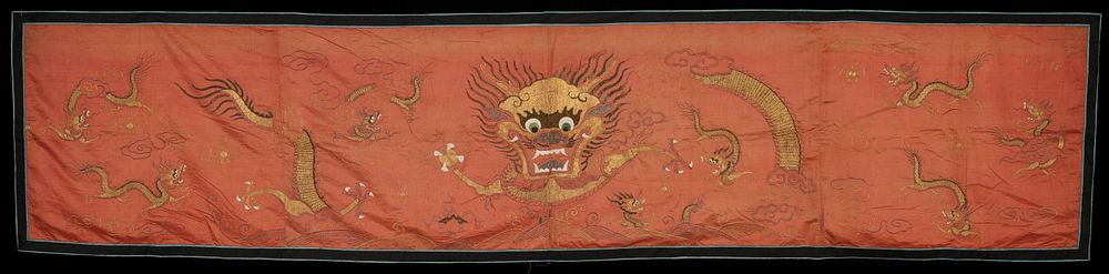 Salmon-colored ground with primarily gold embroidered dragons; large dragon with green eyes at center; black and blue…