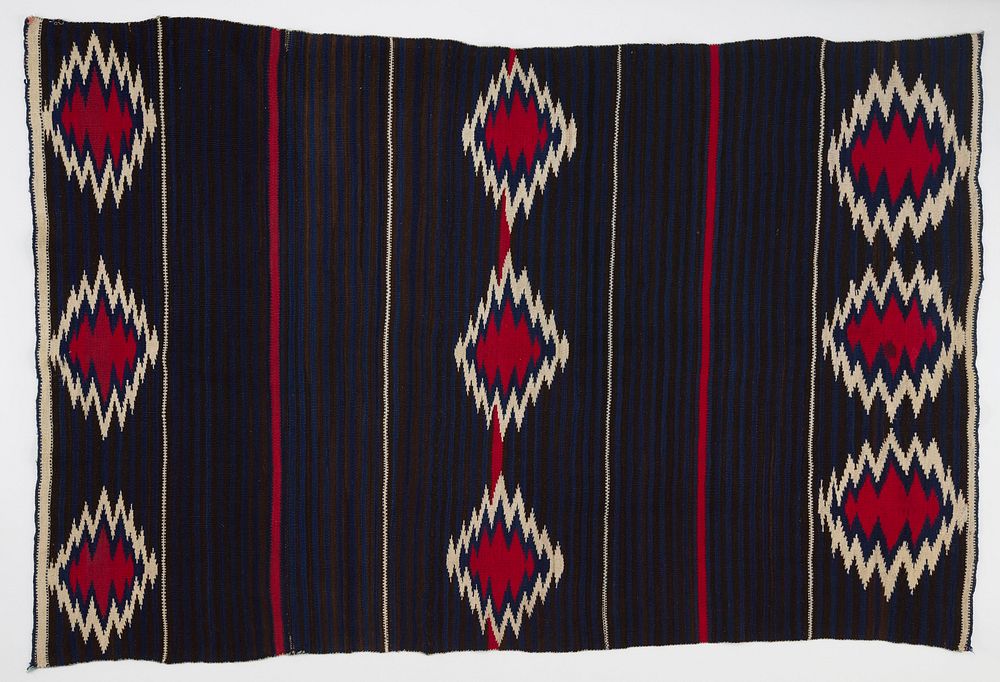 three lines of three large red and white ikat shapes; dark background of alternating black and navy blue bands; thinner…