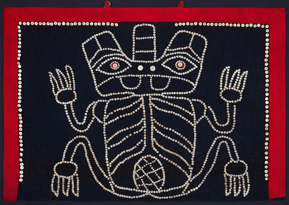 stylized frog-like figure outlined in buttons against navy blue background; red border; figure has three-pronged head, and…