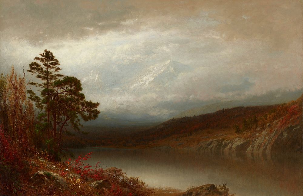 landscape with lake in foreground with brown mountains on opposite shore; tall snow-covered mountain peaks in background…