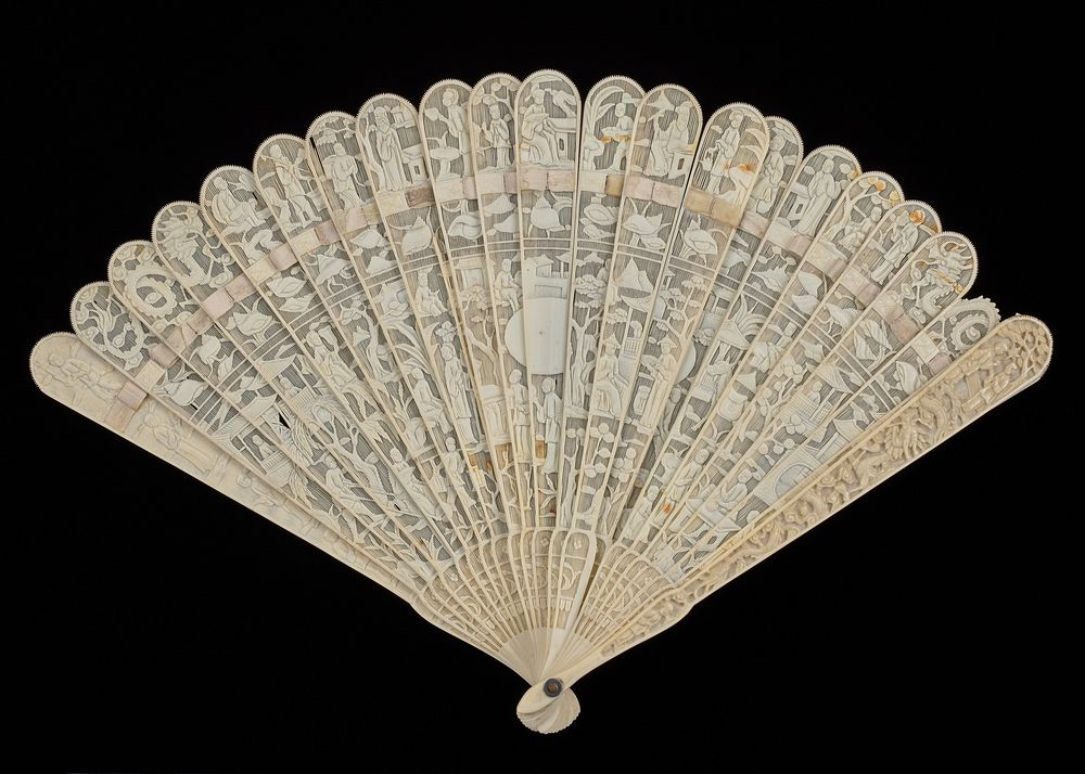 folding fan of ivory with cream colored ribbon at top of ribs; lacy openwork design; empty cartouche at center; Chinese…