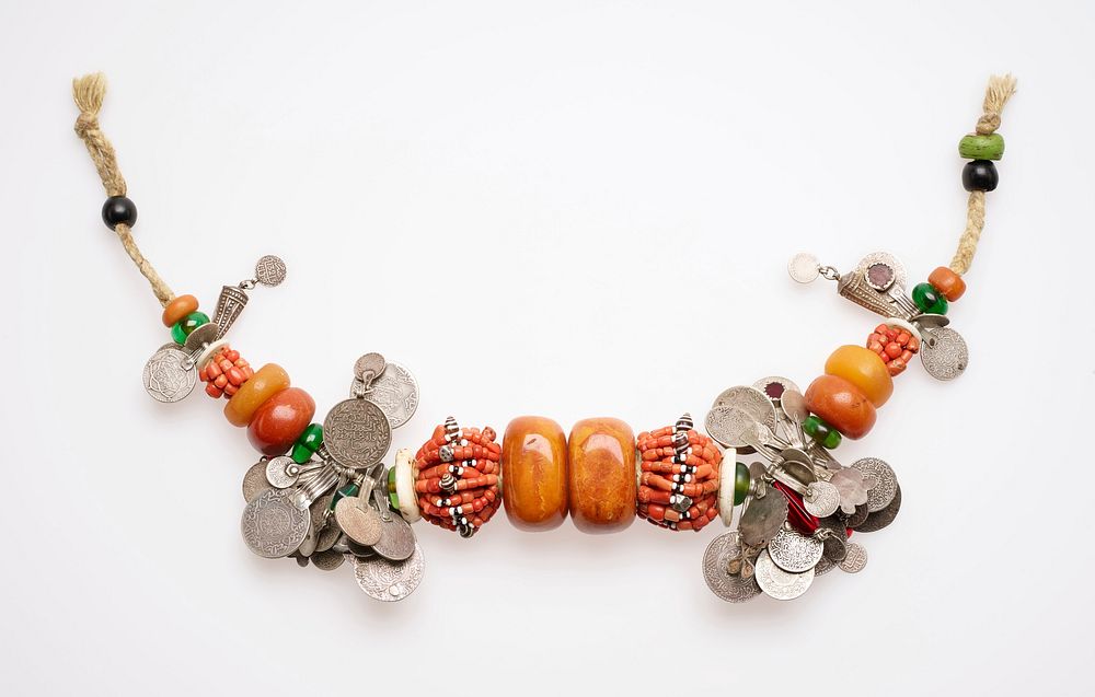 two large central orange amber beads flanked by large group of stringed beads; coins mounted to hanging arms and smaller…