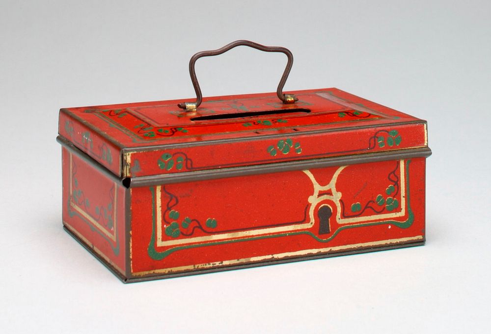 red metal box with handle on top; lid opens; coin slot in top; green vines with leaves painted on top and sides;. Original…