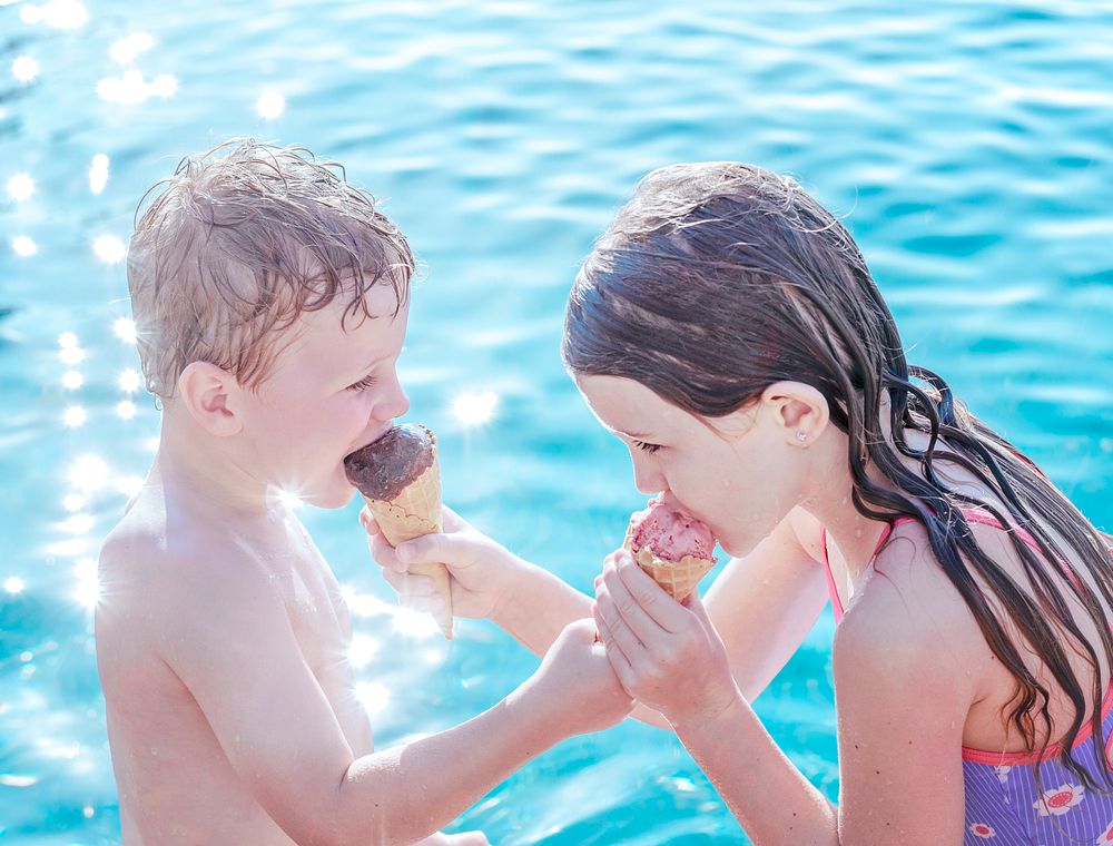 Children sharing ice cream by the pool