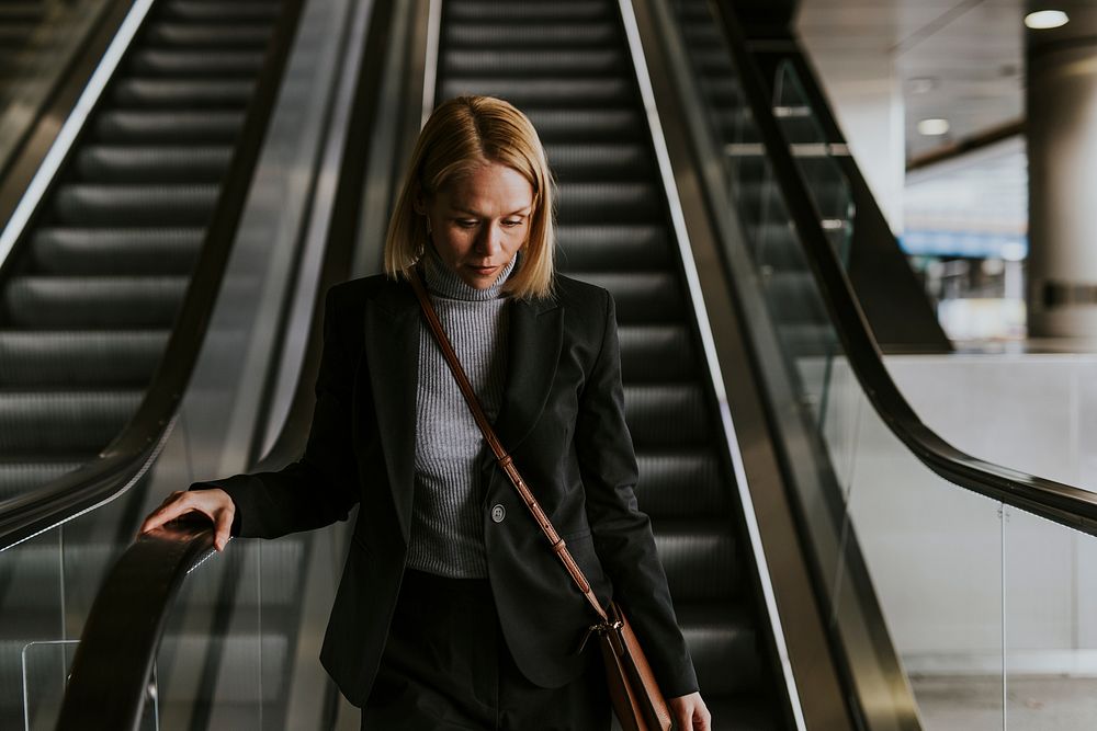 Businesswoman walking down escalator, getting off work