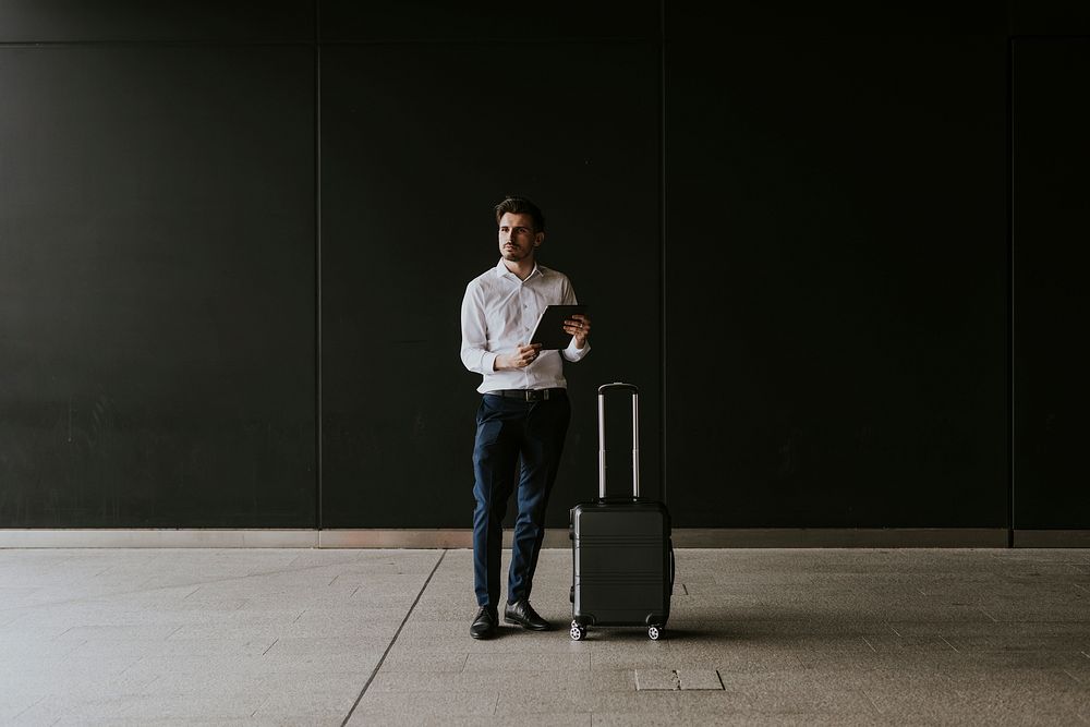 Businessman using tablet, travel luggage
