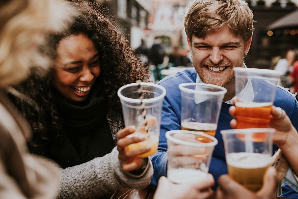 Diverse friends celebrating in pub, drinking beer