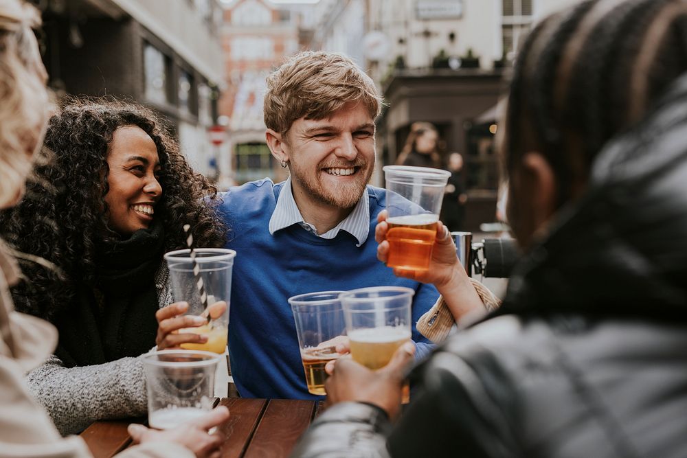 Diverse friends celebrating in pub, drinking beer