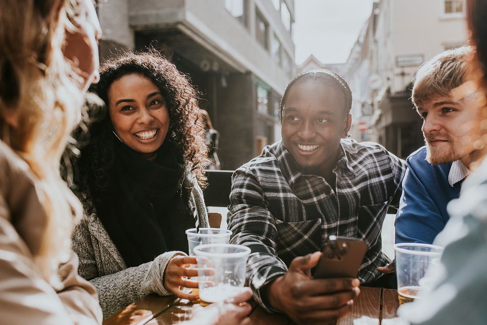 Diverse friends celebrating in pub, drinking beer