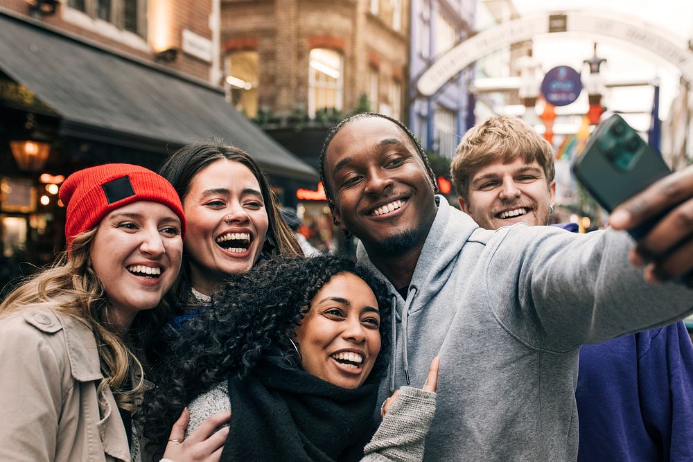 Happy diverse friends taking selfies in the city