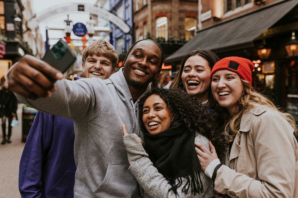 Happy diverse friends taking selfies in the city