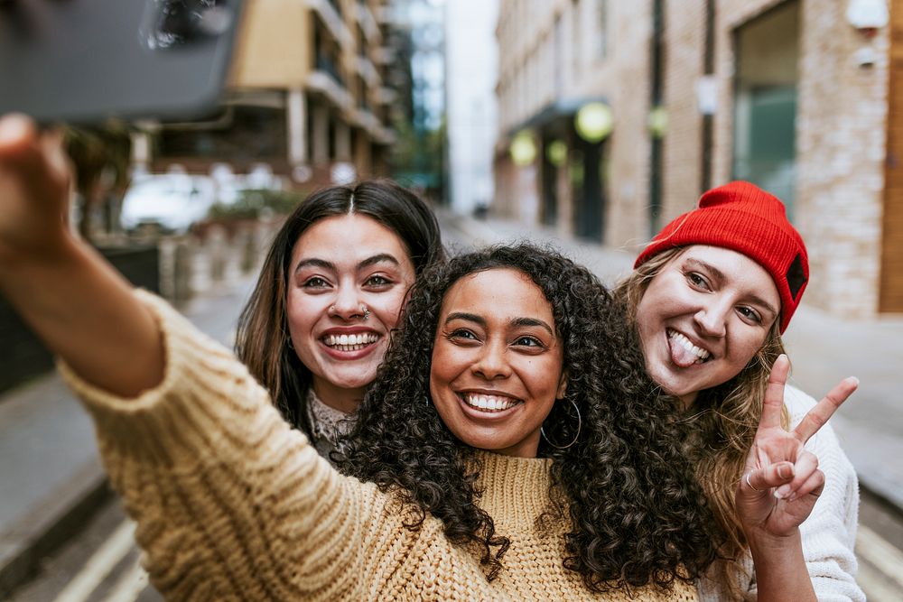Happy girl friends selfie in city, diverse people