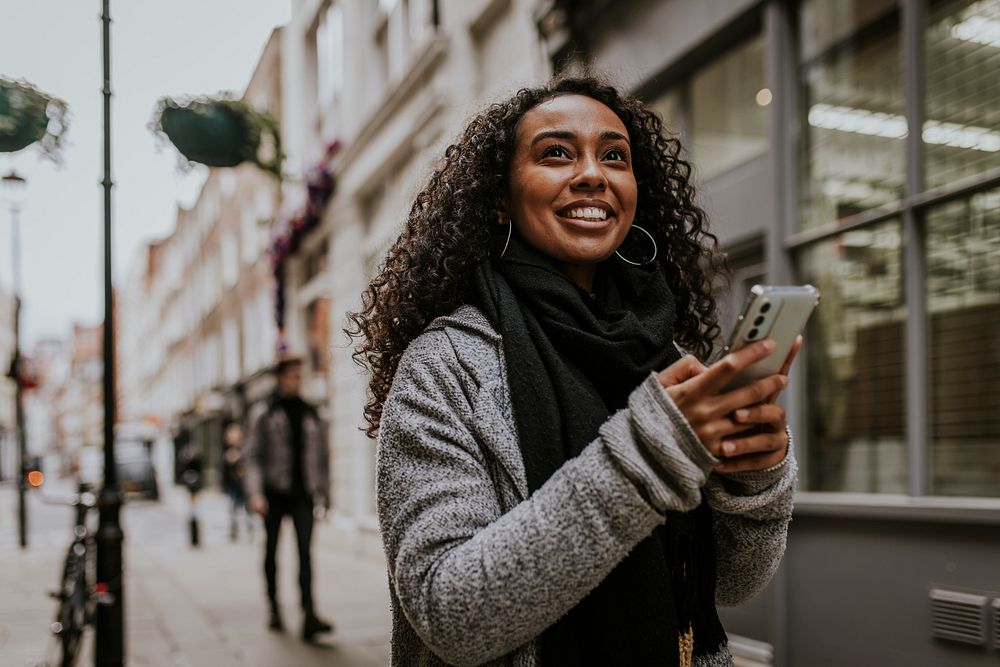 Woman holding mobile phone, walking in the city