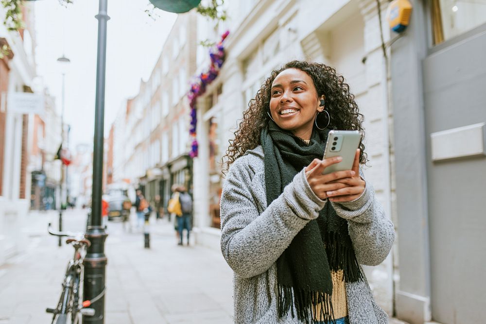 African American woman using smartphone, walking in city