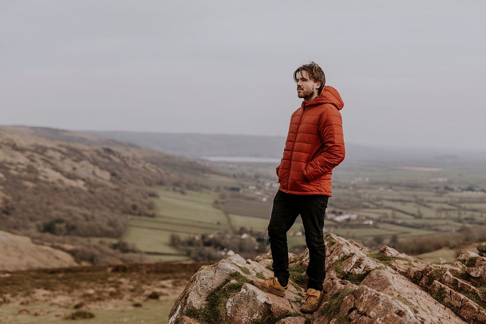Man in orange puffer jacket, standing on mountain