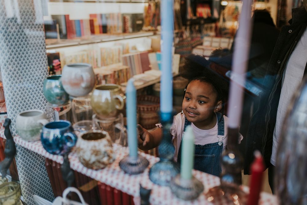 Little girl looking at antique, shopping with mum