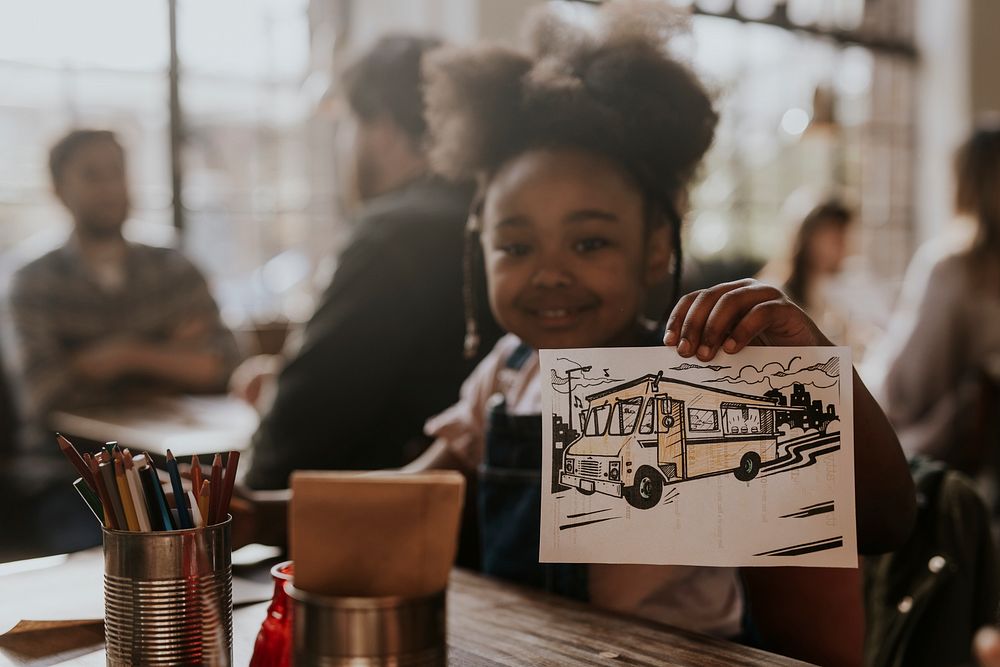 Little girl showing her drawing at a restaurant