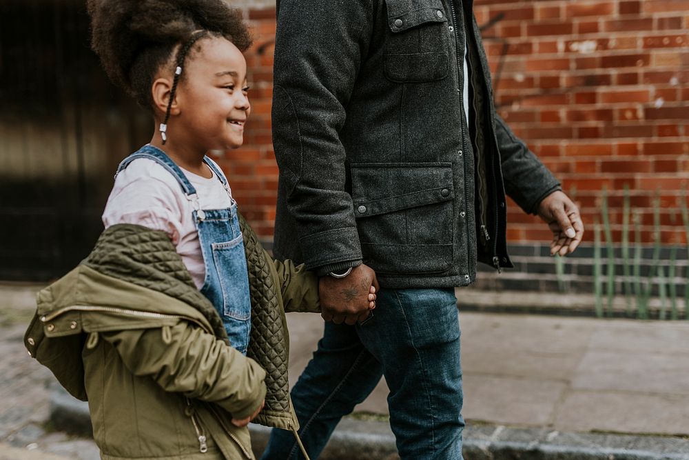 Daughter holding dad's hand, walking in city