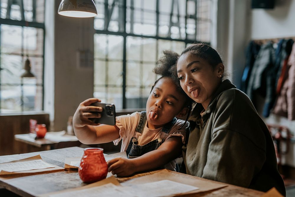 Girl siblings taking selfies at restaurant