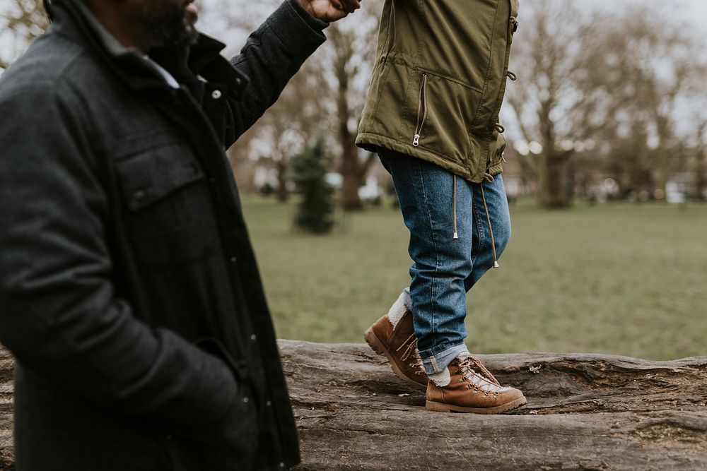 Dad holding daughter's hand, walking on tree stump