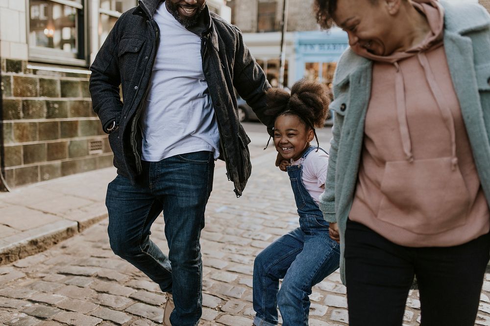 Happy black family walking daughter in city