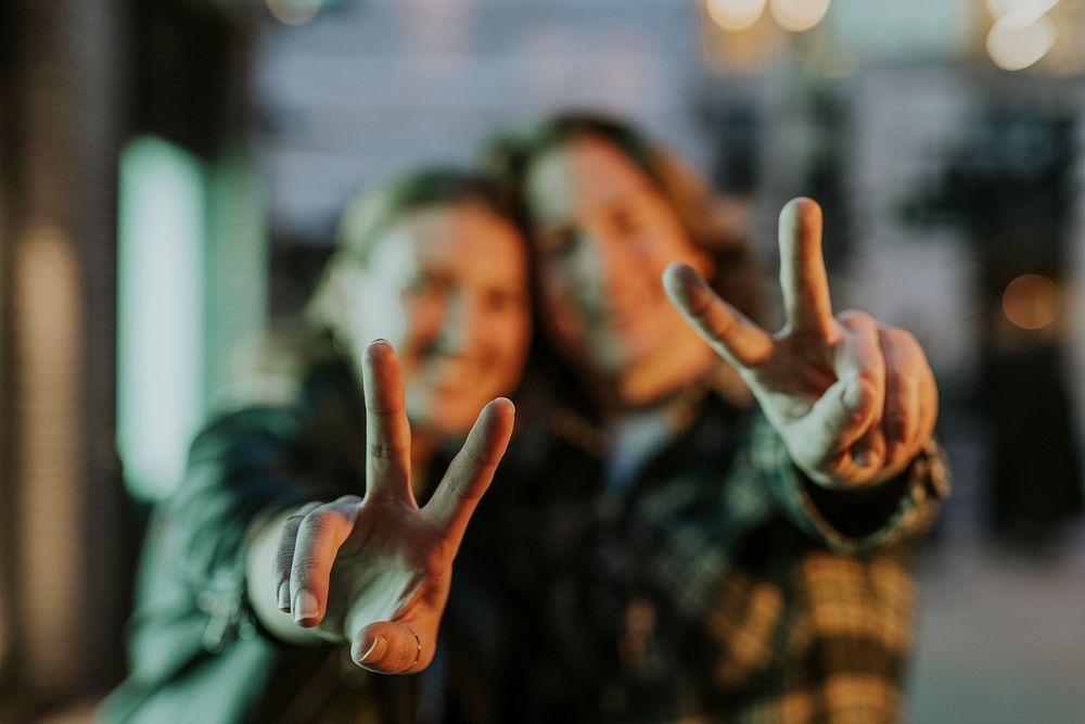 Couple showing peace signs, blurry photo
