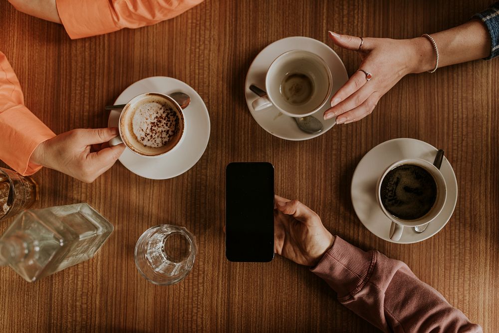 Man holding smartphone, coffee cups on table