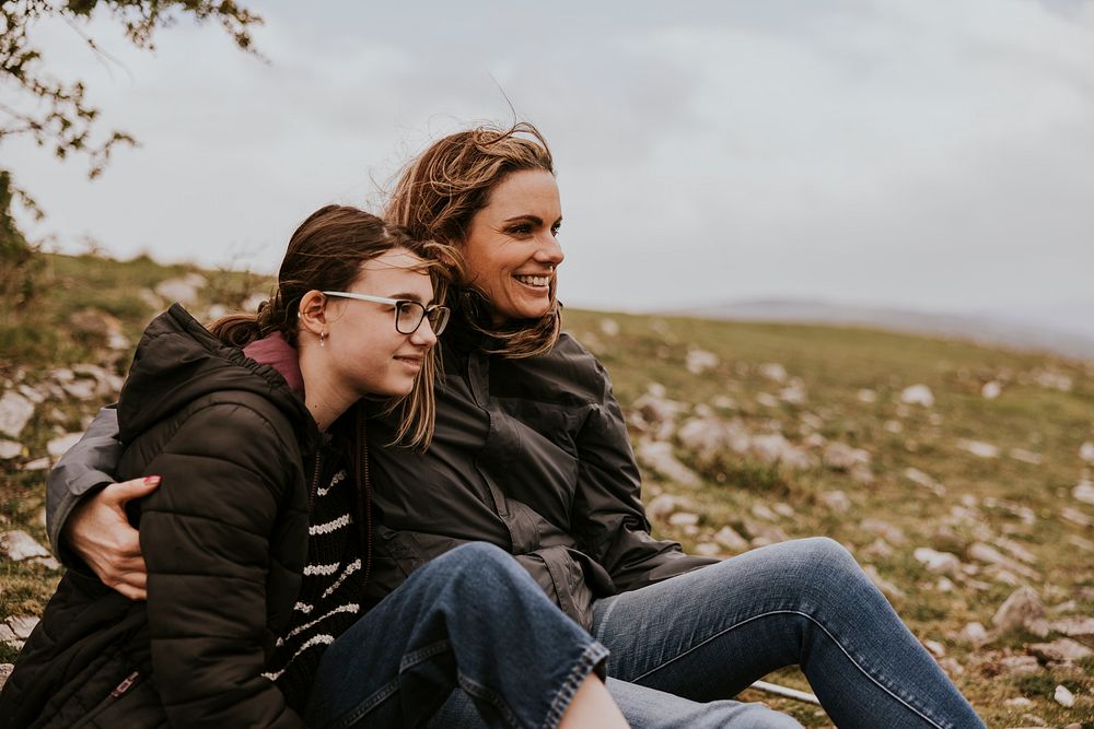 Mother & daughter sitting on hill