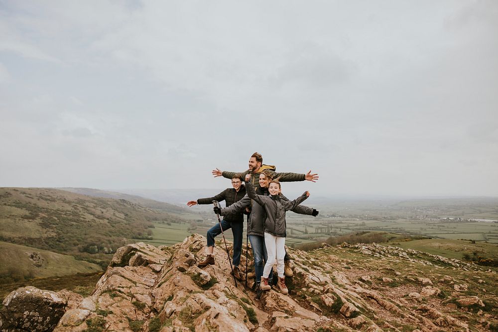 Happy family standing on mountain, outdoor activity