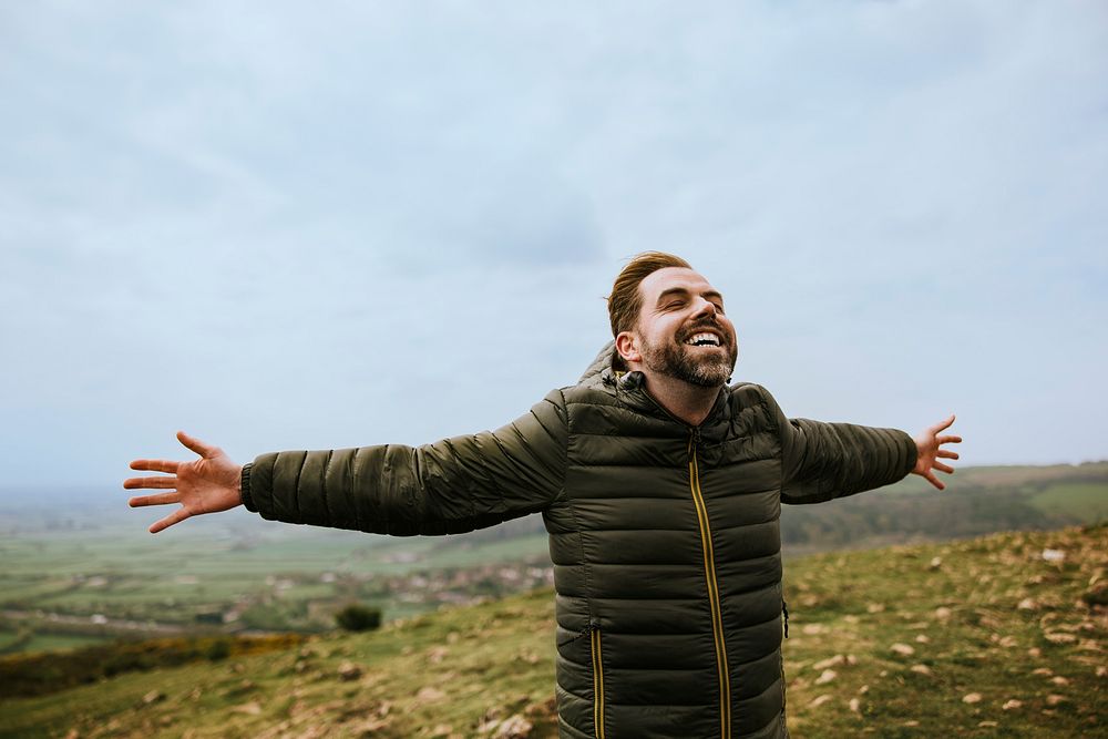 Happy man spreading arms on mountain