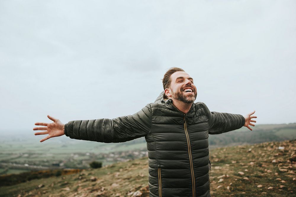 Happy man spreading arms on mountain