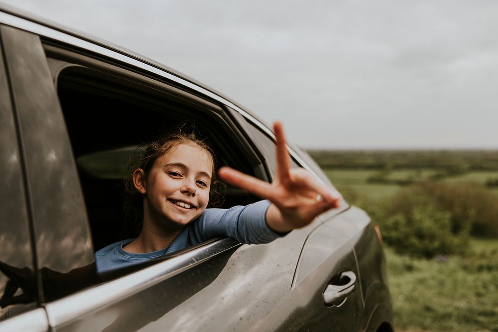 Smiling girl sticking hand out of car photo