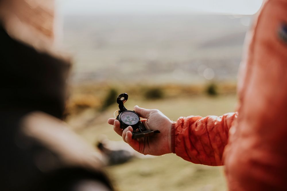 Hiker holding compass on hill photo