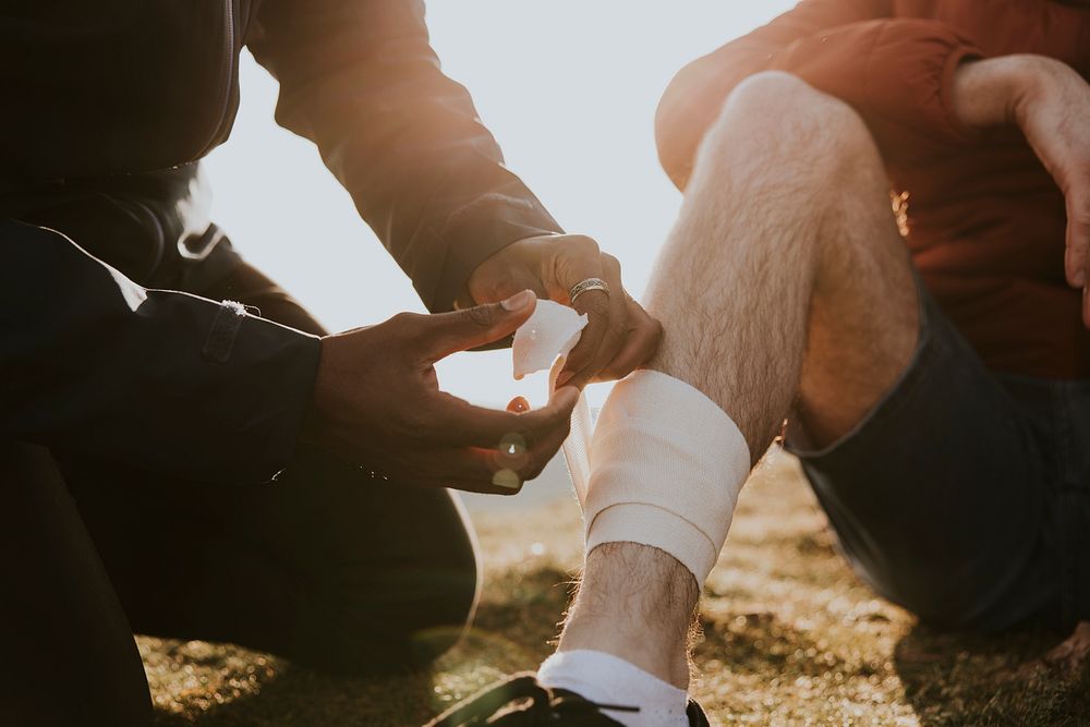 Man putting bandage on friend's leg photo