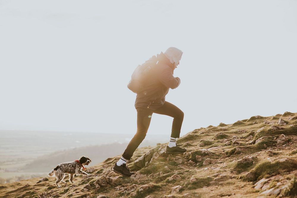 Man walking up mountain with dog photo