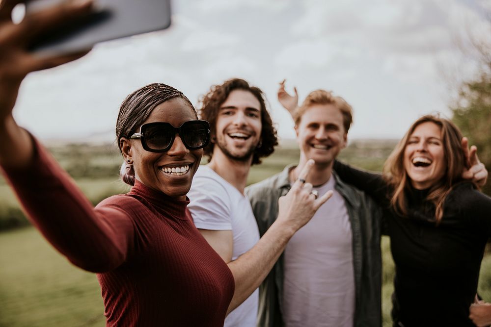 Happy diverse friends taking selfies on smartphone