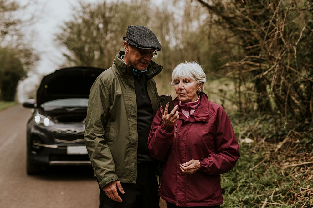 Senior woman calling mechanic, car broken down