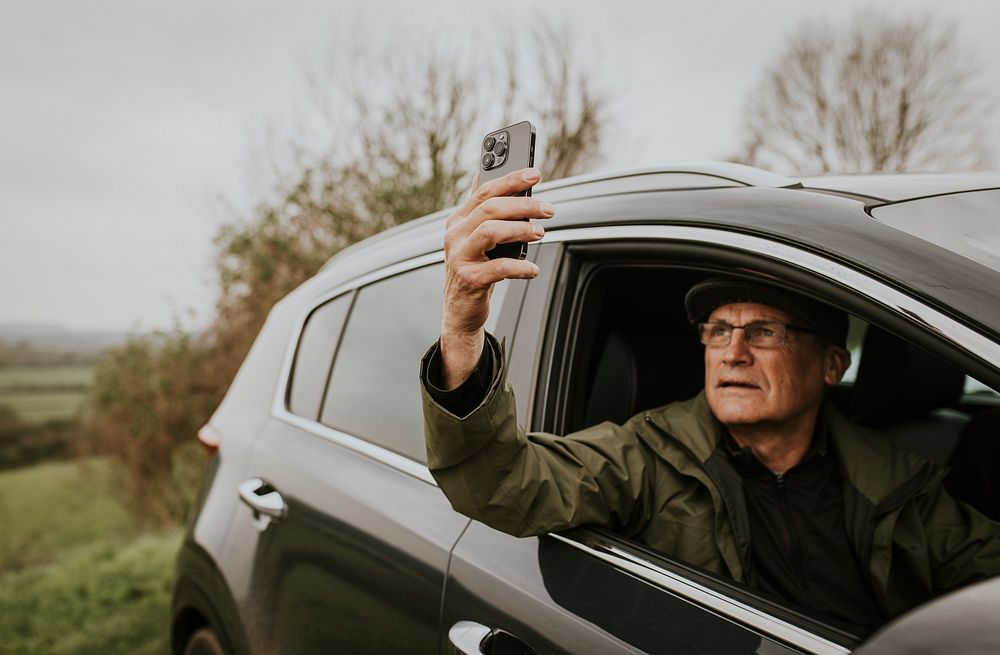 Senior man driving, using GPS on smartphone