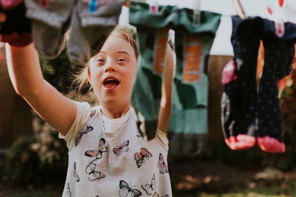 Girl with Down Syndrome hanging laundry, house chore
