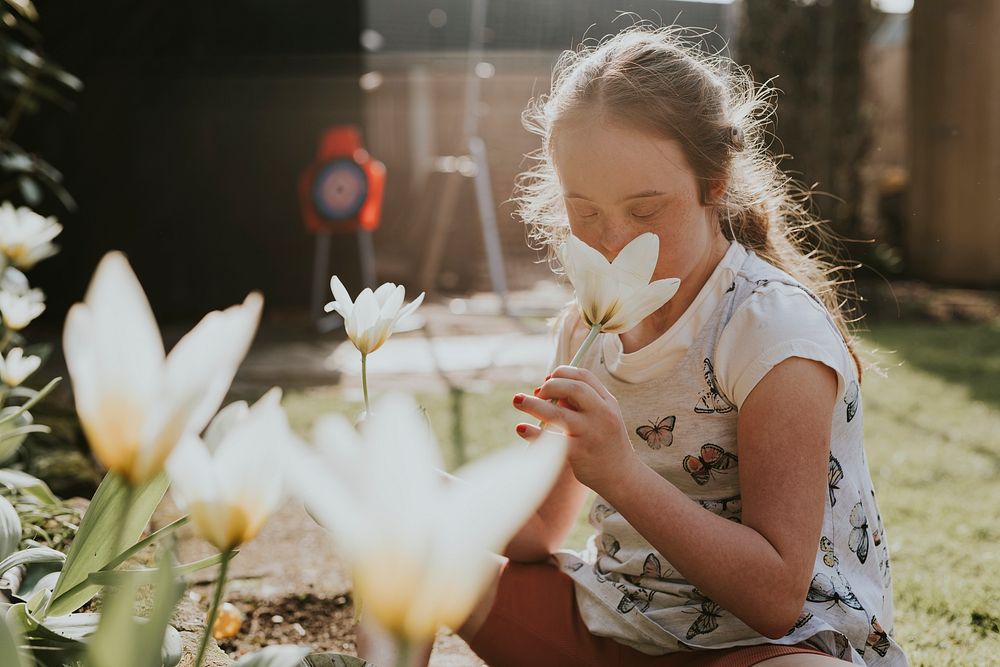 Down syndrome girl smelling flower