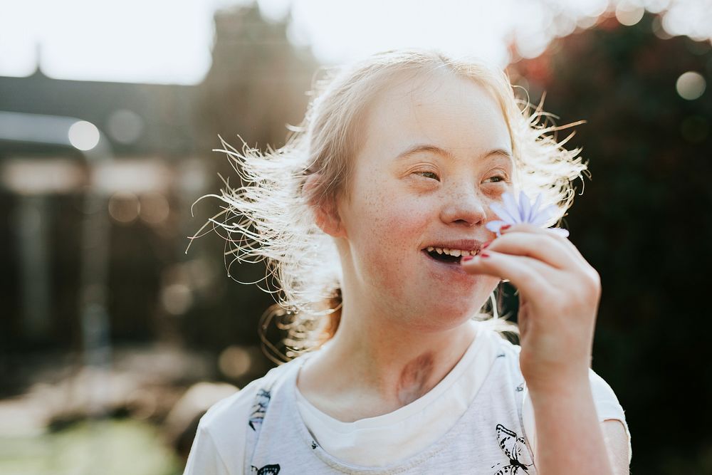 Happy girl with down syndrome smelling flower