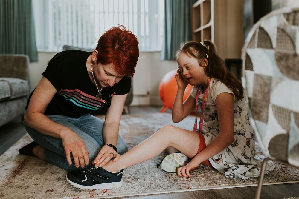 Mum putting shoes for daughter, down syndrome awareness