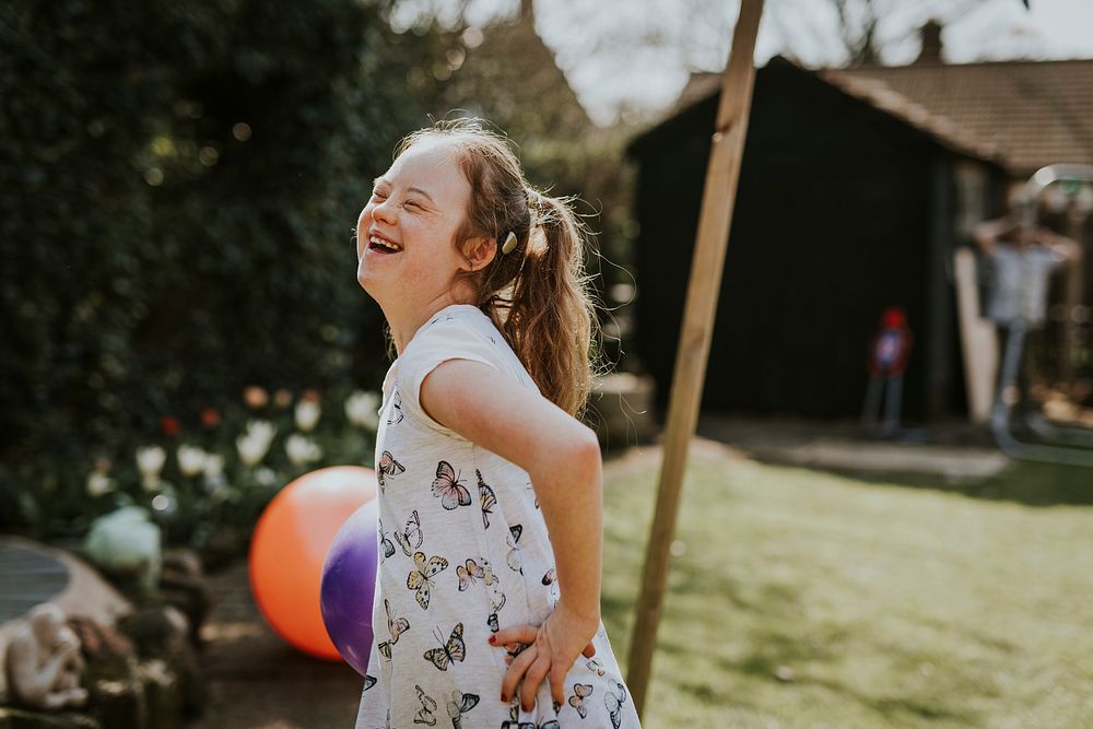 Cheerful girl with Down Syndrome playing in the backyard