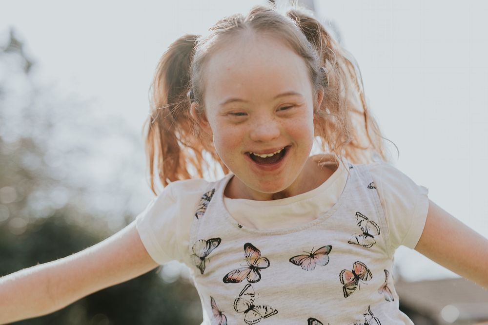 Cheerful girl with Down Syndrome playing in the backyard