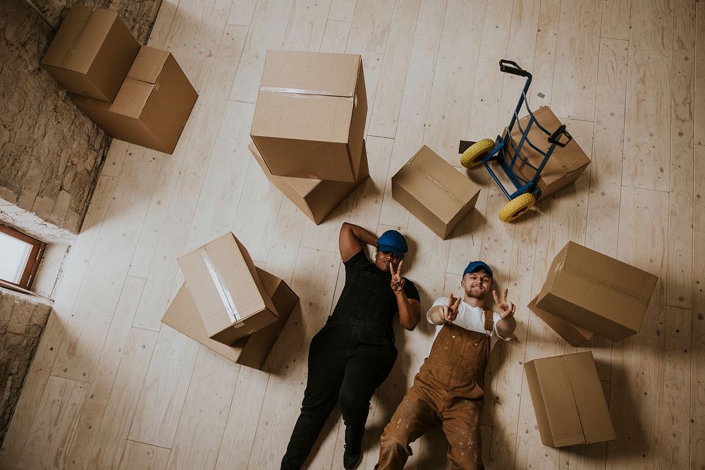 Happy moving service workers lying down on the floor
