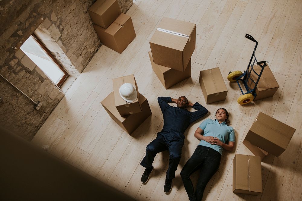 Happy moving service workers lying down on the floor