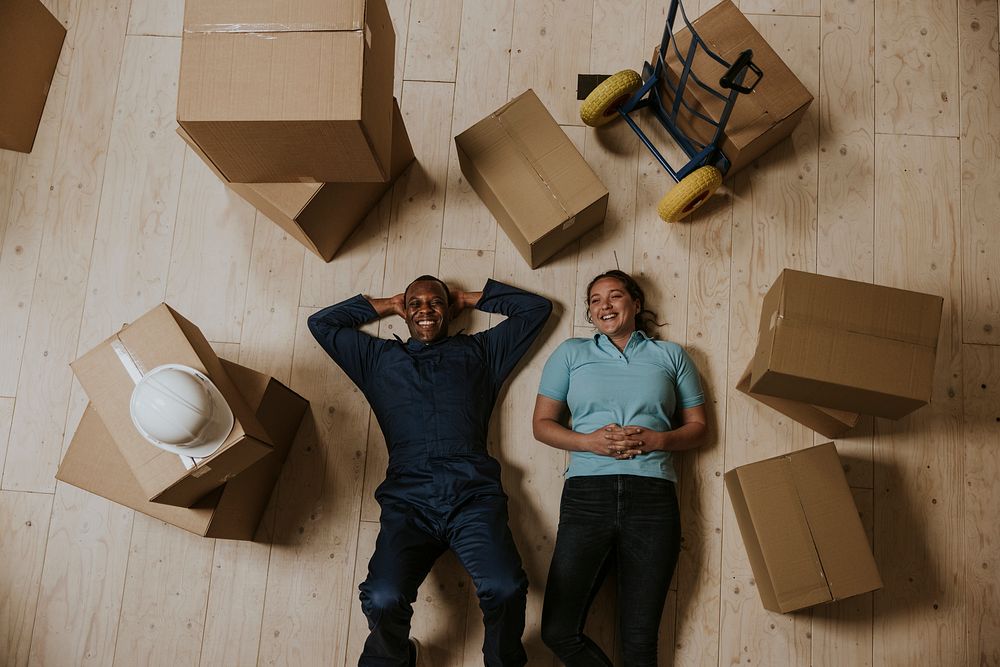 Happy moving service staff lying on the floor