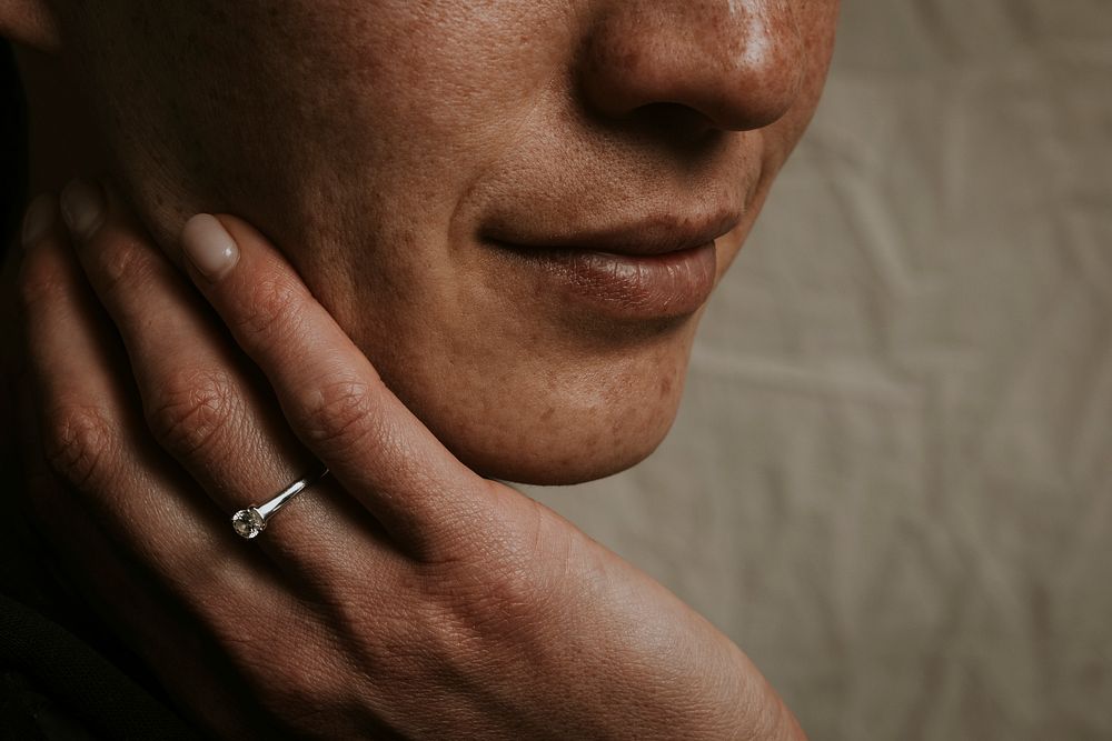 Closeup female wearing ring, touching face photo